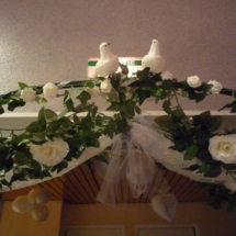 arche pour mariés décoré avec des feuilles, du voile et des colombes