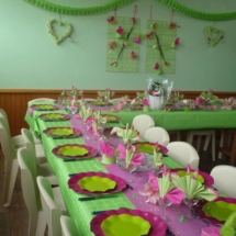 décoration de table thème majorette avec nappe de couleur verte, chemin de table rose fushia brillant, de petits chapeaux de majorettes en carton et bâtons de majorette décorés