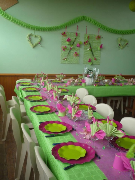 décoration de table thème majorette avec nappe de couleur verte, chemin de table rose fushia brillant, de petits chapeaux de majorettes en carton et bâtons de majorette décorés