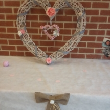 gros coeur en paille décoré avec un ruban gris et des fleurs en tissus