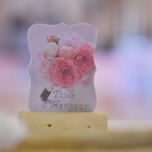 marque place en bois flotté et dessin de pivoines identiques aux fleurs sur la table et le bouquet de la mariée