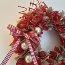 les décorations ( boules de noël, tiges pailletées rouge et noeud vichy ) ont été posées seulement d'un côté de la couronne