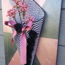 cône en tissus zébré noir et blanc avec un noeud en satin vieux rose et un ruban de fleurs en dentelle noire, le tout posé sur un cadre en bois aux couleurs noir et or rose asymétriques.