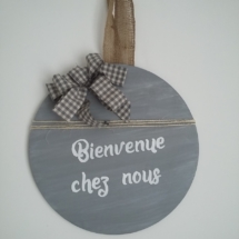 décor de porte en bois rond peint en couleur gris et une très légère patine blanche, un gros noeud Vichy gris, inscription blanche, le tout tenu par un ruban en toile de jute.