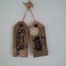 plaque de porte en bois brut avec inscriptions salle de bain et un dessin d'une baignoire peint en noire, le tout tenu par une cordelette