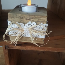 porte bougie en bois entouré d'une jolie dentelle blanche, d'un noeud en raphia surmonté d'un petit bouton de fleur