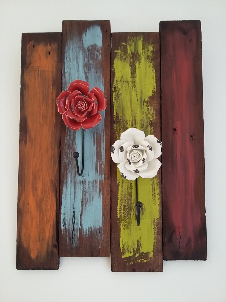 porte serviettes en bois teinté foncé et coups de peinture pour un effet peps avec patères en forme de fleurs en porcelaine de couleur rouge et blanche