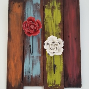 porte serviettes en bois teinté foncé et coups de peinture pour un effet peps avec patères en forme de fleurs en porcelaine de couleur rouge et blanche