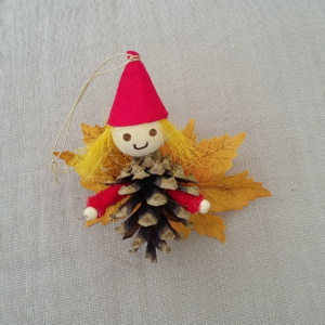 petit lutin ailé à suspendre fabriqué avec des pommes de pin, une perle de bois pour la tête, des feuilles de couleur jaune pour les ailes et un petit chapeau pointu de couleur rouge