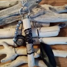Bijoux de sac avec bois flotté, perles, ornement et plume noire.