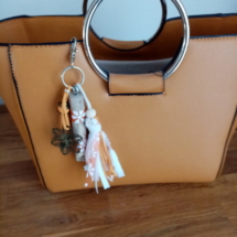 Bijoux de sac en bois flotté avec perles, ornement et pompons en tissus couleur orangé.