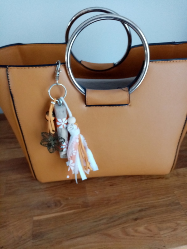 Bijoux de sac en bois flotté avec perles, ornement et pompons en tissus couleur orangé.