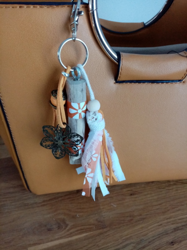 Bijoux de sac en bois flotté avec perles, ornement et pompons en tissus couleur orangé.