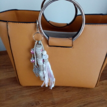 Bijoux de sac avec bois flotté, dentelle, perles, ornement et pompon en tissus couleur rose.