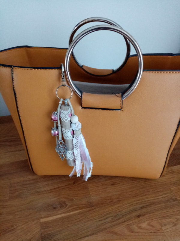 Bijoux de sac avec bois flotté, dentelle, perles, ornement et pompon en tissus couleur rose.