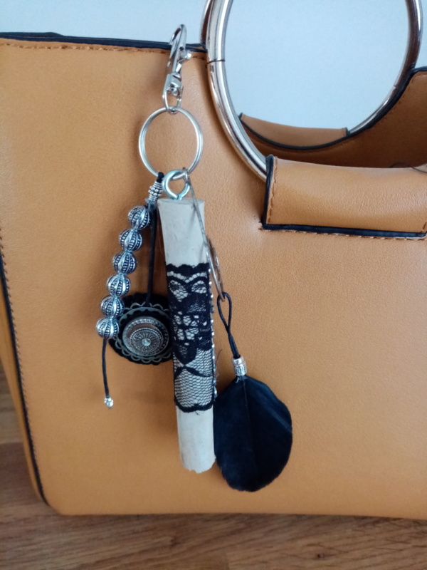 Bijoux de sac avec bois flotté, perles, ornement et plume noire.