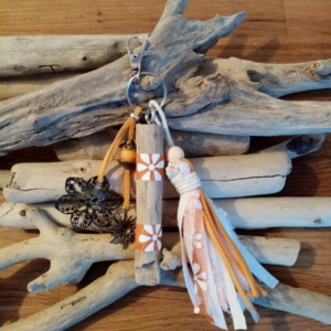 Bijoux de sac en bois flotté avec perles, ornement et pompons en tissus couleur orangé.