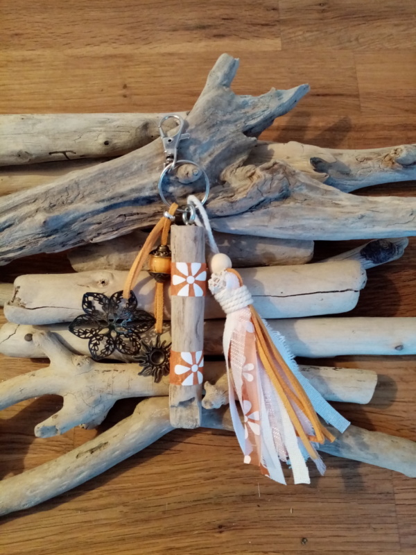 Bijoux de sac en bois flotté avec perles, ornement et pompons en tissus couleur orangé.