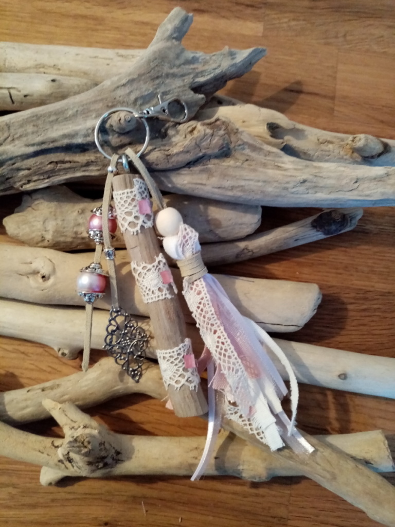 Bijoux de sac avec bois flotté, dentelle, perles, ornement et pompon en tissus couleur rose.