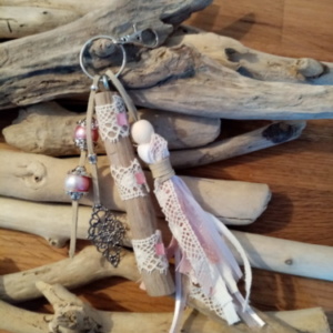 Bijoux de sac avec bois flotté, dentelle, perles, ornement et pompon en tissus couleur rose.
