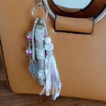 Bijoux de sac avec bois flotté, dentelle, perles, ornement et pompon en tissus couleur rose.