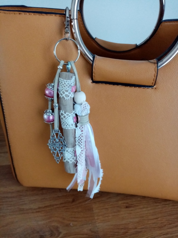 Bijoux de sac avec bois flotté, dentelle, perles, ornement et pompon en tissus couleur rose.