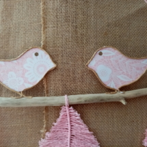 Deux petits oiseaux en fil de kraft armé posés sur une branche de bois flotté.