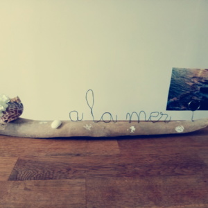 Porte photo avec écriture en fil de fer, à la mer, posé sur du bois flotté