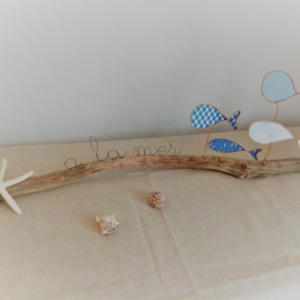 Décoration sur le thème de mer avec poissons en fil de kraft arme couleur bleue posés délicatement sur une branche de bois flotté. Une étoile de mer est collée à l'extrémité du bois.