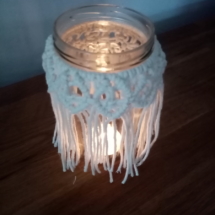 Petit bougeoir en macramé illuminé avec une bougie chauffe plat.