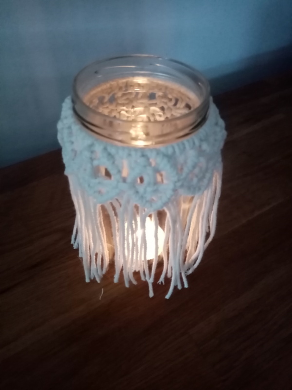 Petit bougeoir en macramé illuminé avec une bougie chauffe plat.