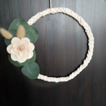 Couronne de macramé tressé avec une fleur en bois et des petites feuilles d'eucalyptus