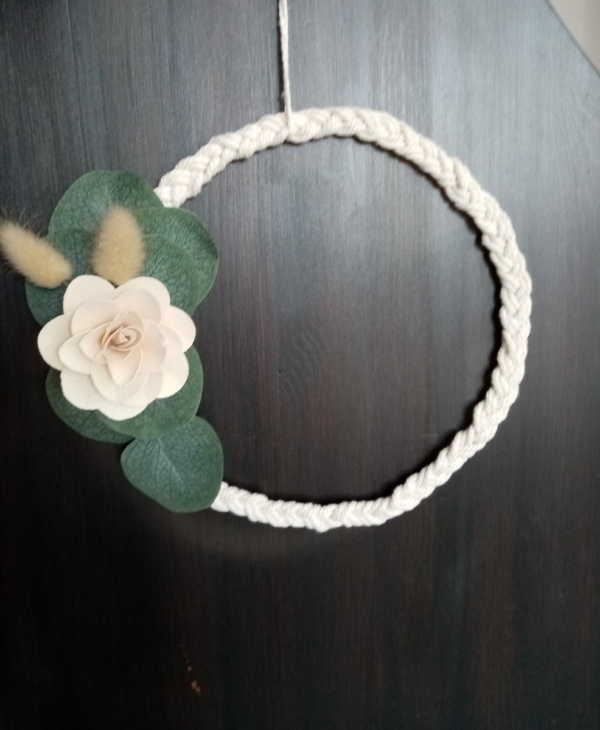 Couronne de macramé tressé avec une fleur en bois et des petites feuilles d'eucalyptus