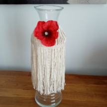 Vase bouteille entouré de macramé et agrémenté d'une fleur de coquelicot