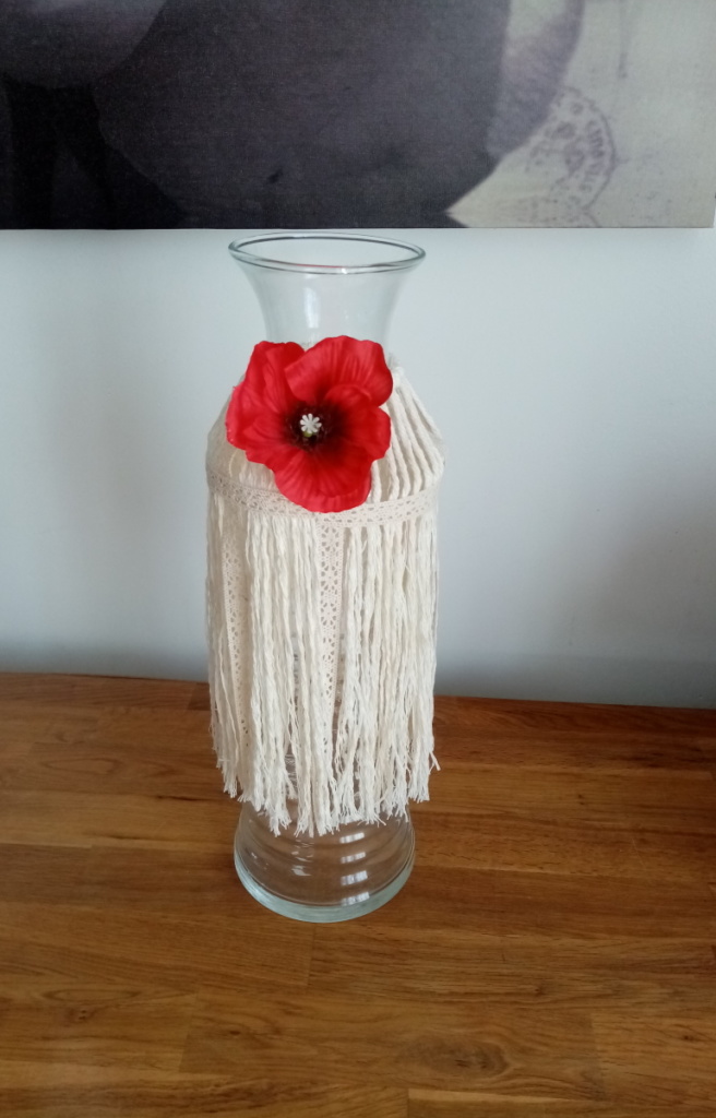 Vase bouteille entouré de macramé et agrémenté d'une fleur de coquelicot