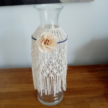Vase bouteille entouré de macramé et agrémenté d'une fleur en bois