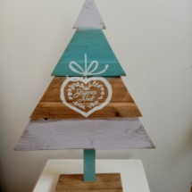 Sapin de noël en bois couleur bois, bleu et naturel avec un coeur dessiné dessus.