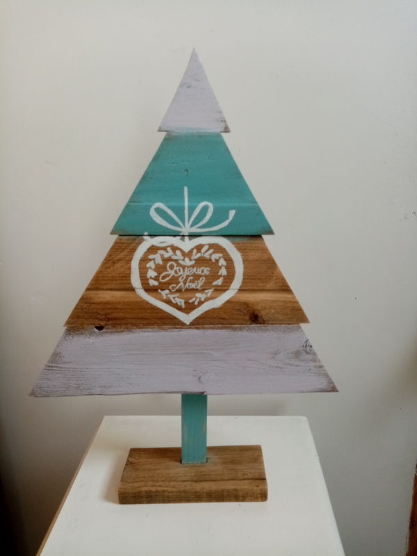 Sapin de noël en bois couleur bois, bleu et naturel avec un coeur dessiné dessus.