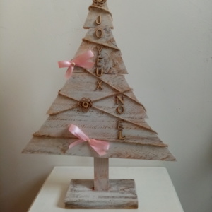 Sapin de noël en bois patiné blanc avec petits ornements en bois et petits noeuds rose.