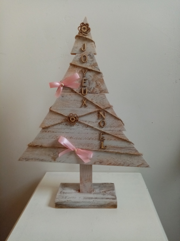 Sapin de noël en bois patiné blanc avec petits ornements en bois et petits noeuds rose.