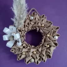 Couronne de noël en toile de jute avec fleur de pampa, branche pailletée, gros noeud et petites boules couleur or.