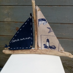 Bateau en bois flotté avec deux voiles. Une voile tissus bleu marine avec inscription en broderie blanche " Berck sur mer" et une autre voile couleur crème et des imprimés bleu marine