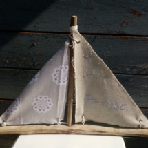 Bateau en bois flotté avec deux voiles en tissus. Une voile en lin et une voile tissus gris fleuri et rose