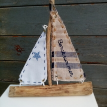 bateau en bois flotté avec deux voiles. Une voile en tissus bleu et crème avec inscription " Berck sur mer" en broderie bleu marine et une autre voile tissus blanc.