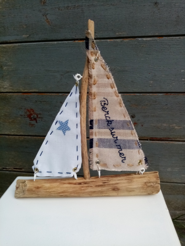 bateau en bois flotté avec deux voiles. Une voile en tissus bleu et crème avec inscription " Berck sur mer" en broderie bleu marine et une autre voile tissus blanc.