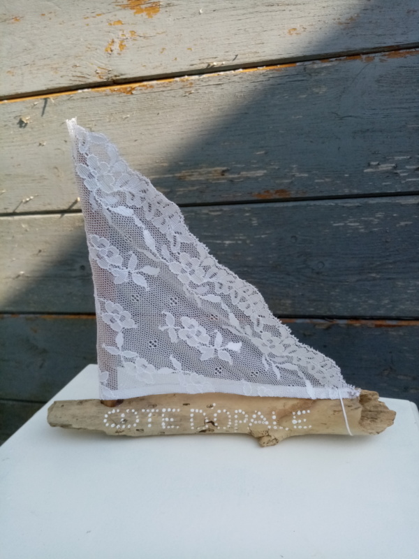 Petit bateau en bois flotté avec une voile en véritable dentelle de Calais. Une inscription " Côte d'Opale" faite avec un outil de pointage d'art et peinture blanche