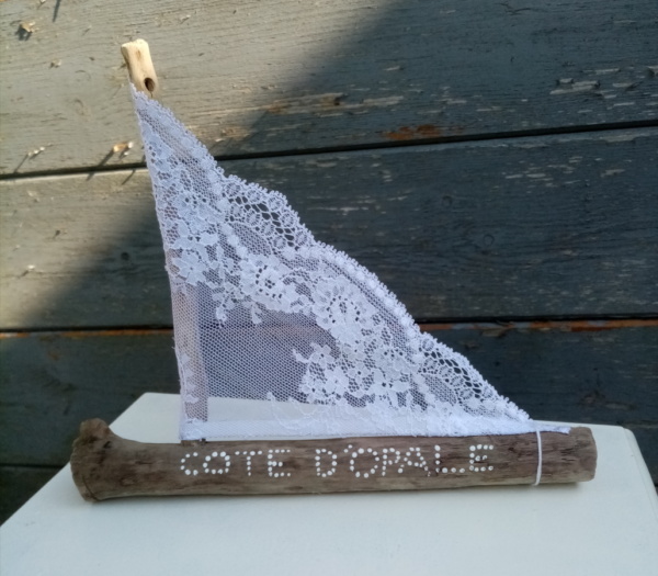 Petit bateau en bois flotté avec une voile en véritable dentelle de Calais. Une inscription " Côte d'Opale" faite avec un outil de pointage d'art et peinture blanche