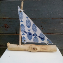 Petit bateau en bois flotté avec une voile tissus imprimé poissons