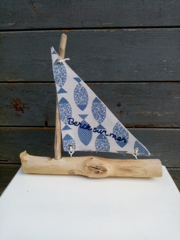 Petit bateau en bois flotté avec une voile tissus imprimé poissons