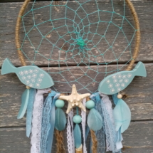 Deux petits poissons en bois chantournés et patinés avec étoile de mer posés sur attrape rêve thème bleu